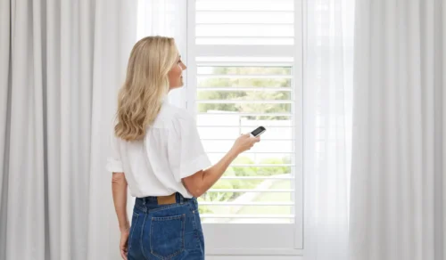 Woman closing her blockout and sheer curtains using her Wynmotion remote.